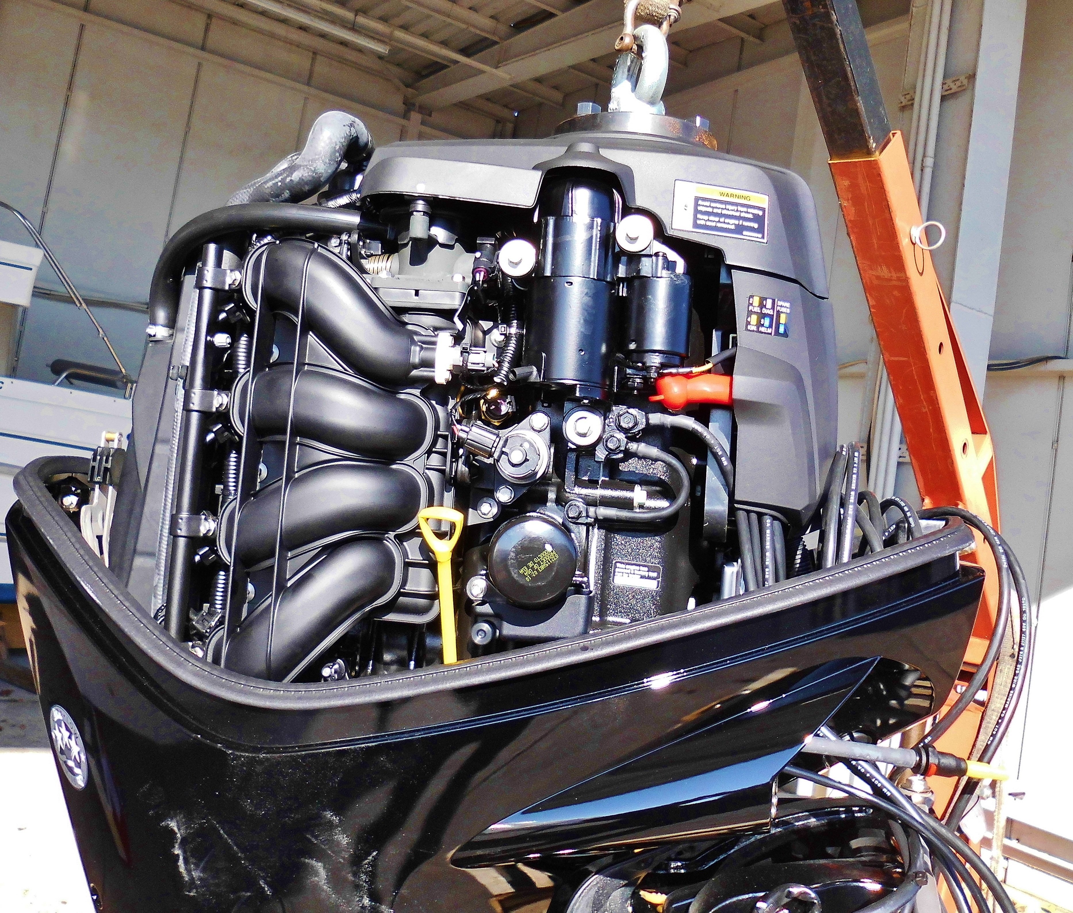 Motoréacteur hors-bord noir avec câblage et organes visibles, posé sur support, vue rapprochée de l’installation et du réservoir. Motoréacteur hors-bord noir avec câblage et organes visibles, posé sur support, vue rapprochée de l’installation et du réservoir.